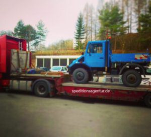 blauer Unimog auf Tieflader LKW