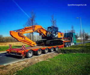 orangener Bagger steht auf Tieflader LKW