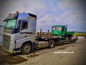 grüner Kipper auf Tieflader LKW