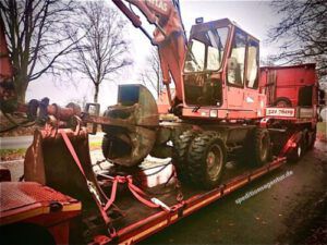 roter Bagger auf Tiefbett LKW