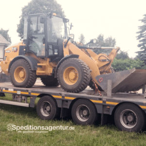 gelber Radlader auf Tieflader LKW