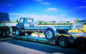 blauer Unimog auf Tiefbett LKW